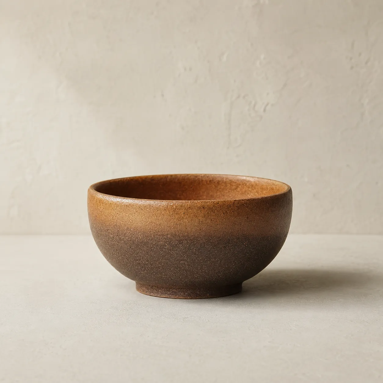 Stoneware bowl with a glaze fading from warm amber at the rim to deep brown at the foot.
